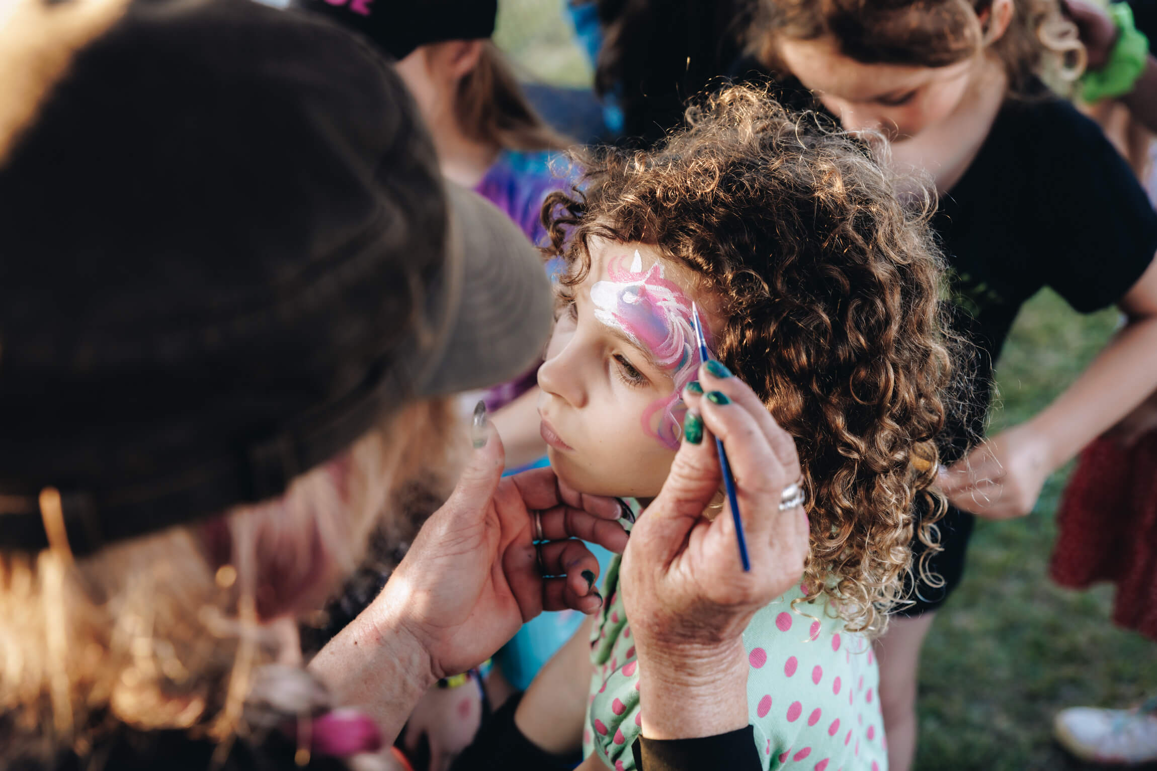 A girl getting a purple and ipink butterfly painted on her face.